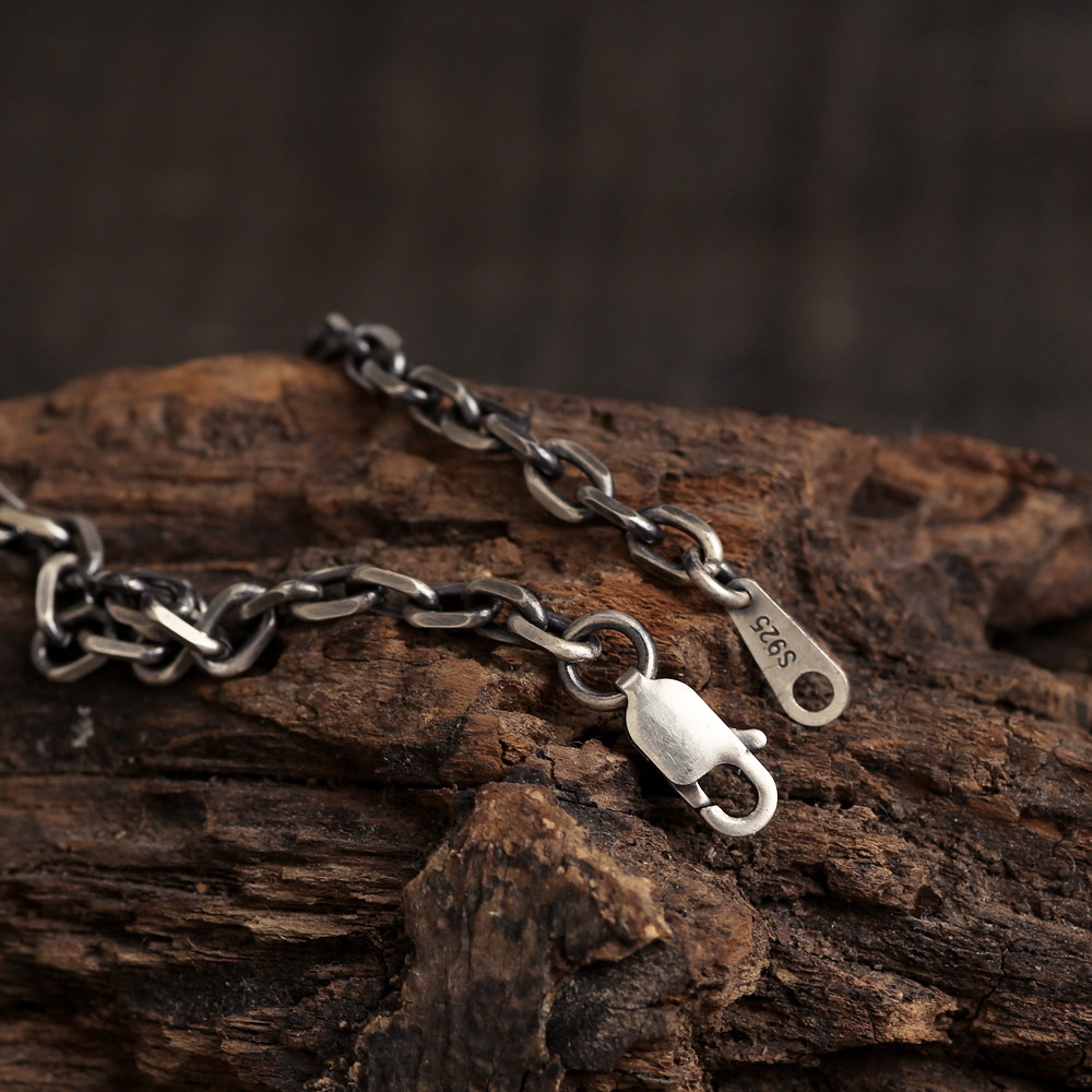 Close-up of the Diamond Cut Curb Chain with an open lobster clasp and S925 tag on rustic wood.