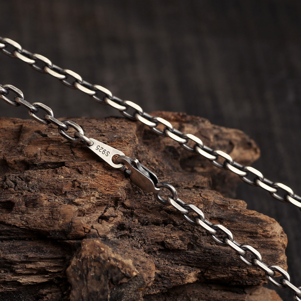 Diamond Cut Curb Chain links draped diagonally across rustic wood, with closed lobster clasp and S925 tag.