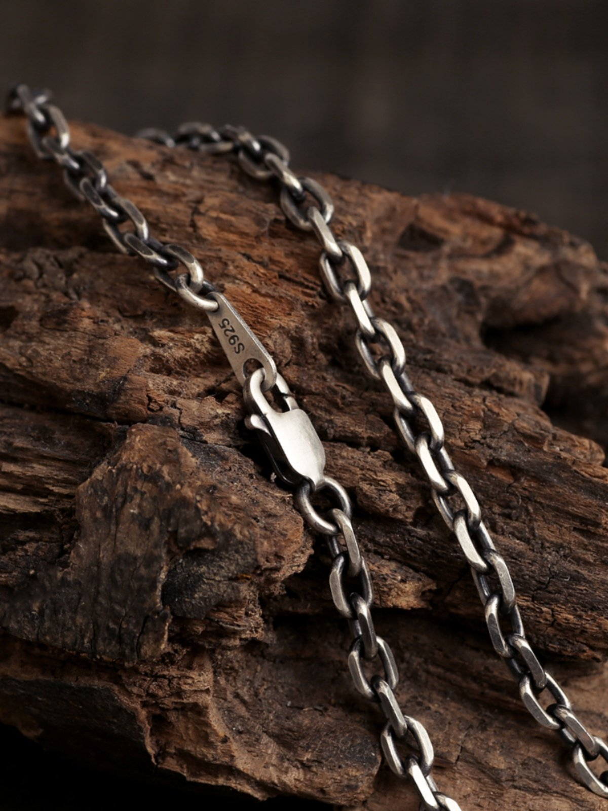 Diamond Cut Curb Chain draped over rustic wood, showing polished link surfaces and lobster clasp.
