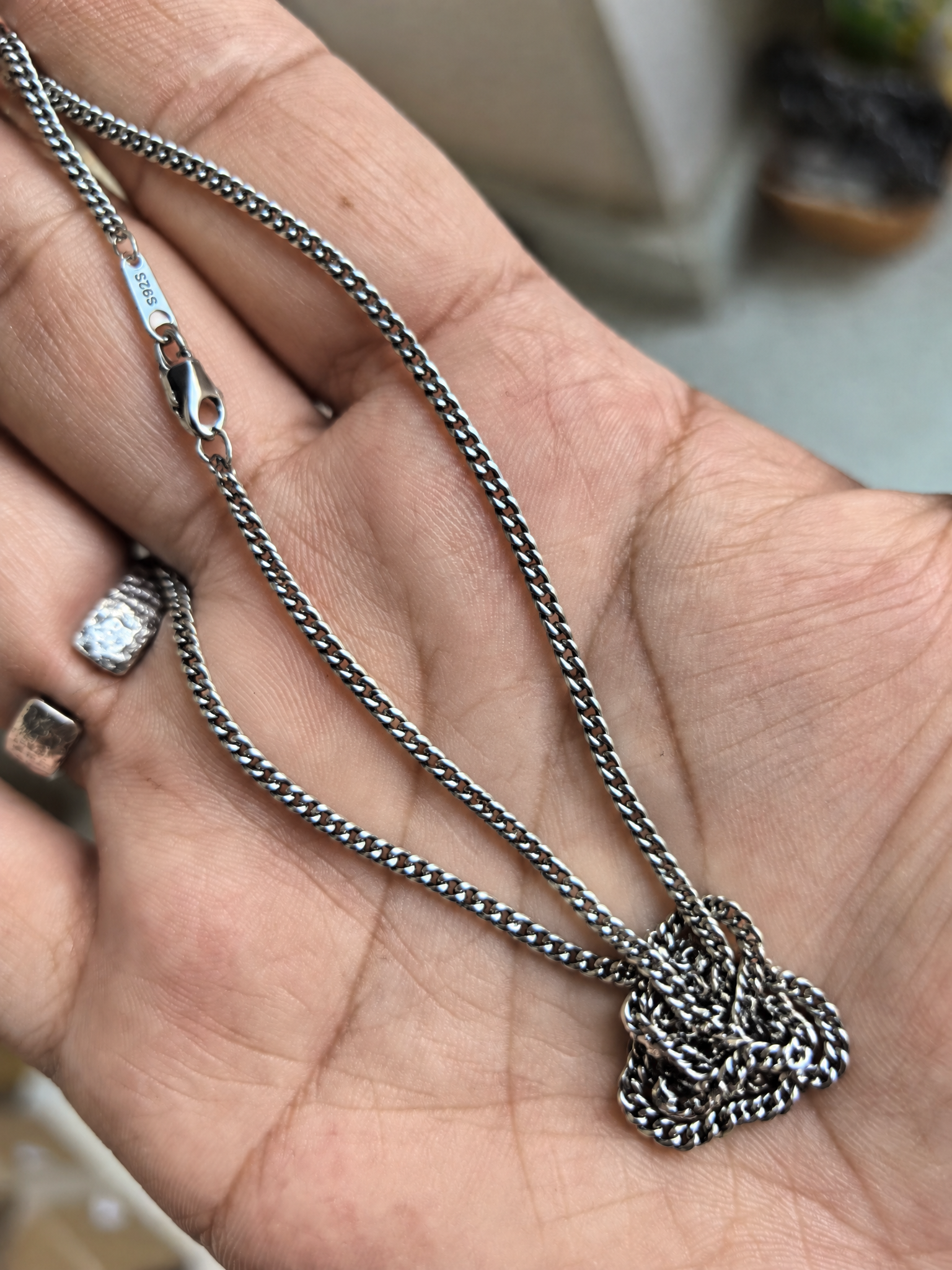 Cuban link chain pooled in an open hand, showing the clasp and S925 tag.